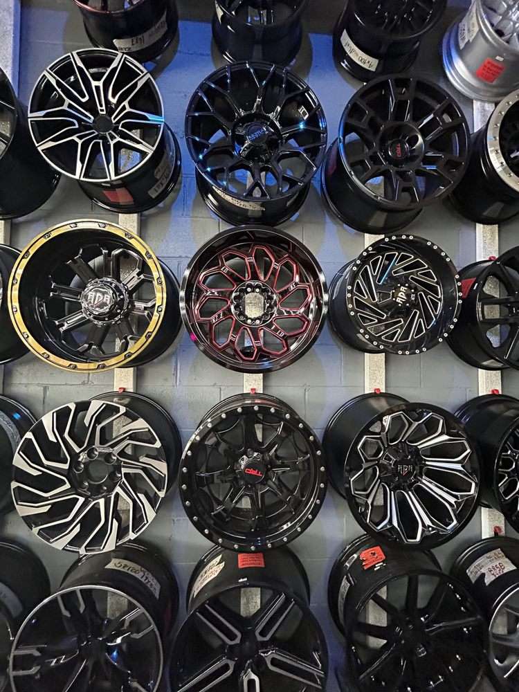 Close-up of black, machined and red-accent alloy rims stacked on the wall at Speed Auto USA